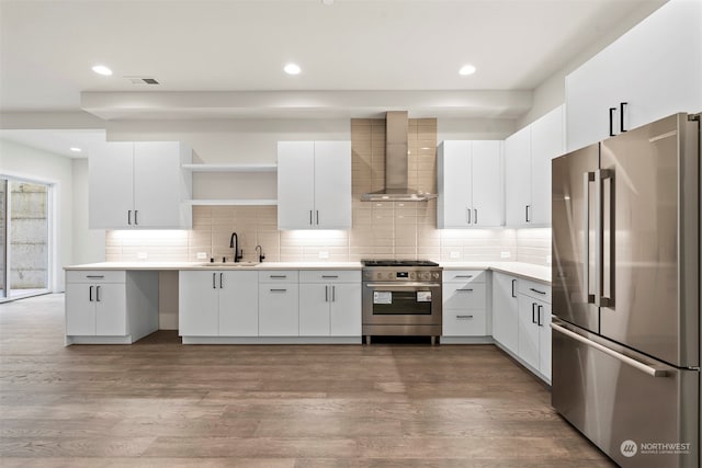 kitchen featuring decorative backsplash, hardwood / wood-style flooring, high end appliances, and wall chimney exhaust hood