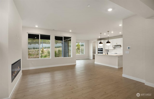 unfurnished living room with sink and light hardwood / wood-style flooring