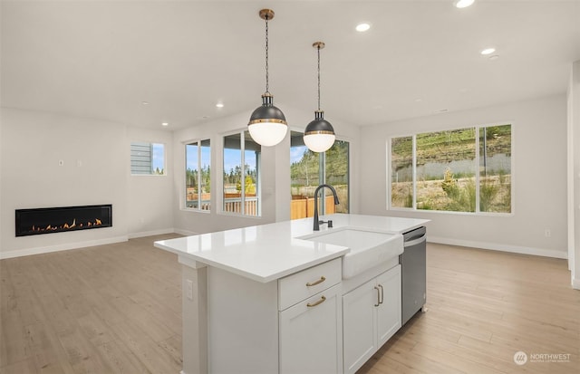 kitchen with sink, dishwasher, a kitchen island with sink, hanging light fixtures, and white cabinets