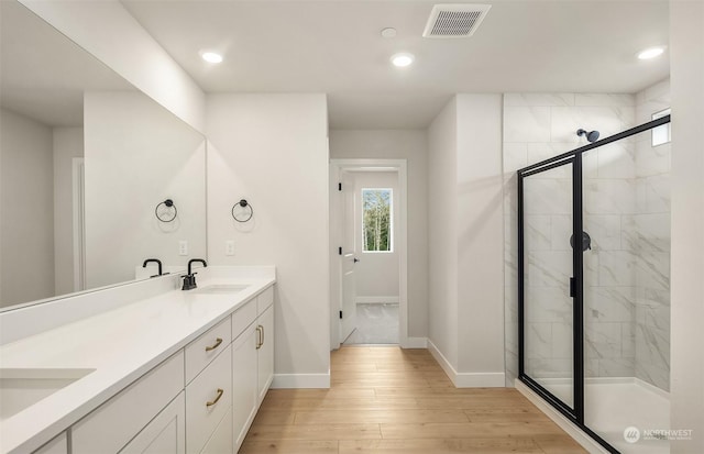 bathroom with hardwood / wood-style flooring, vanity, and walk in shower