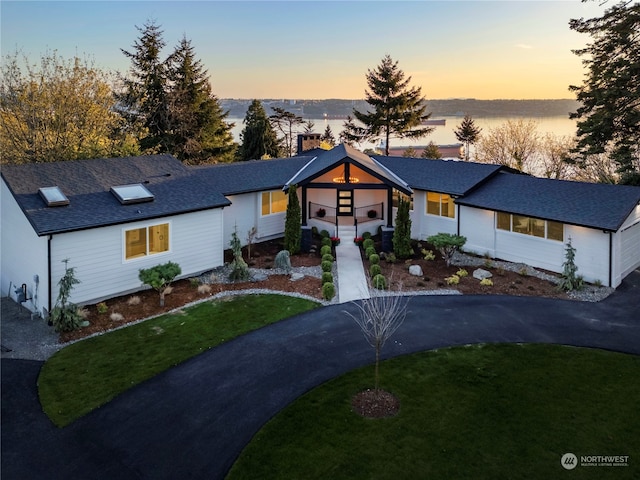 view of front of house featuring a water view and a lawn