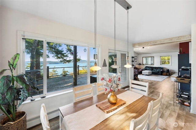 dining area featuring beam ceiling, light hardwood / wood-style floors, french doors, and a water view