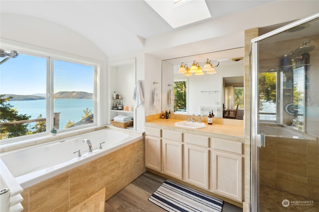 bathroom featuring hardwood / wood-style floors, a skylight, a water view, shower with separate bathtub, and large vanity