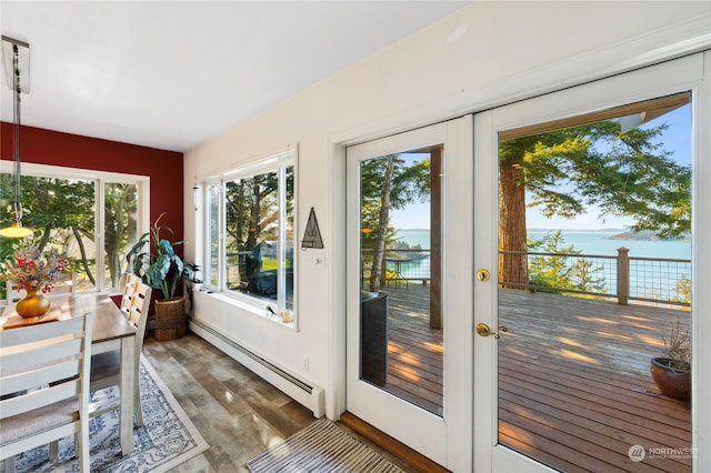 sunroom / solarium with baseboard heating, a water view, and french doors