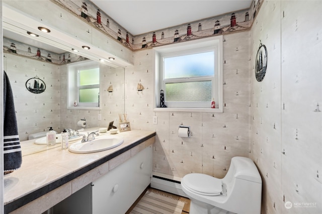 bathroom featuring baseboard heating, toilet, and vanity with extensive cabinet space