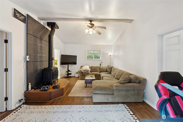 living room with vaulted ceiling with beams, dark wood-type flooring, ceiling fan, and a wood stove