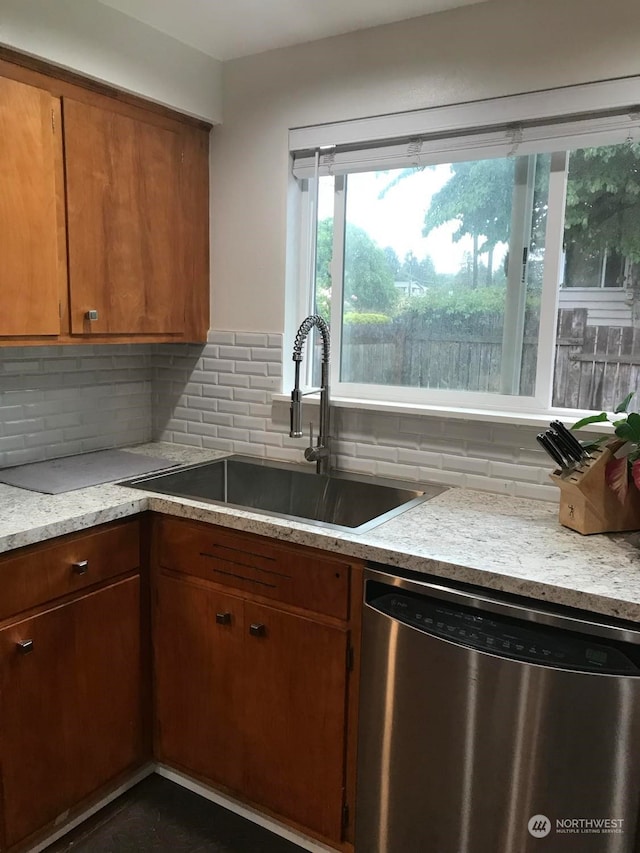 kitchen with backsplash, sink, light stone countertops, and stainless steel dishwasher