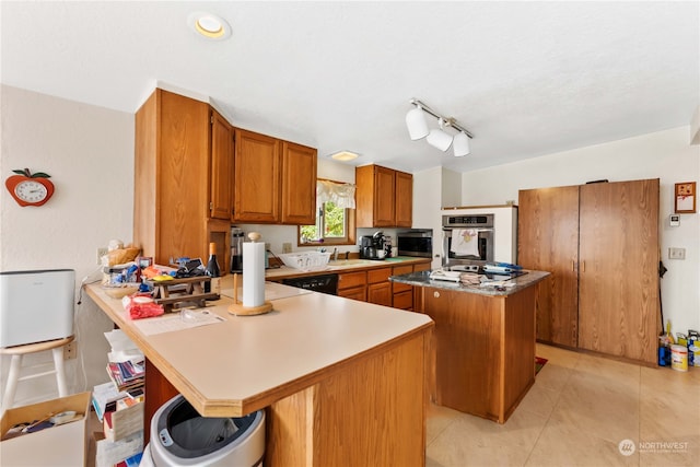 kitchen with a kitchen island, a kitchen breakfast bar, rail lighting, stainless steel oven, and light tile floors