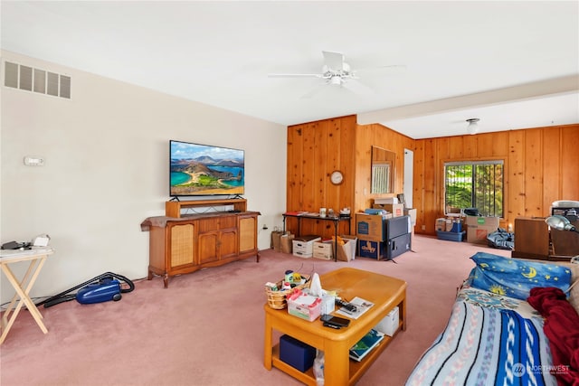 living room with wood walls, carpet, and ceiling fan