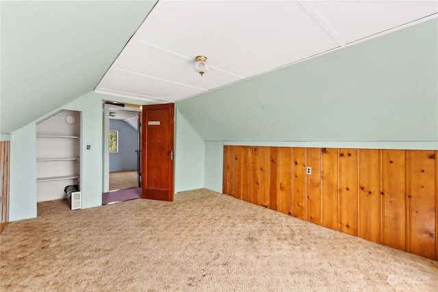 additional living space featuring carpet floors, lofted ceiling, wooden walls, and built in features