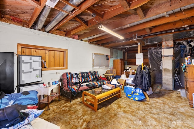 unfinished basement with freestanding refrigerator