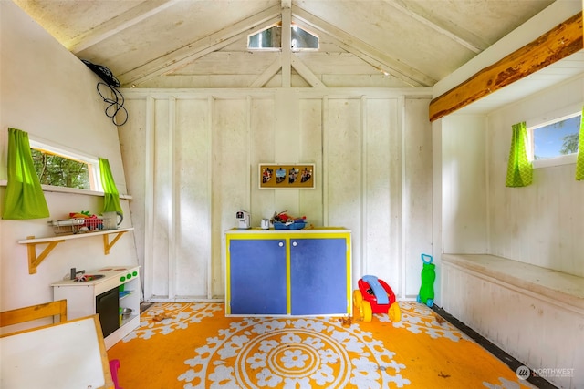 recreation room featuring vaulted ceiling with beams