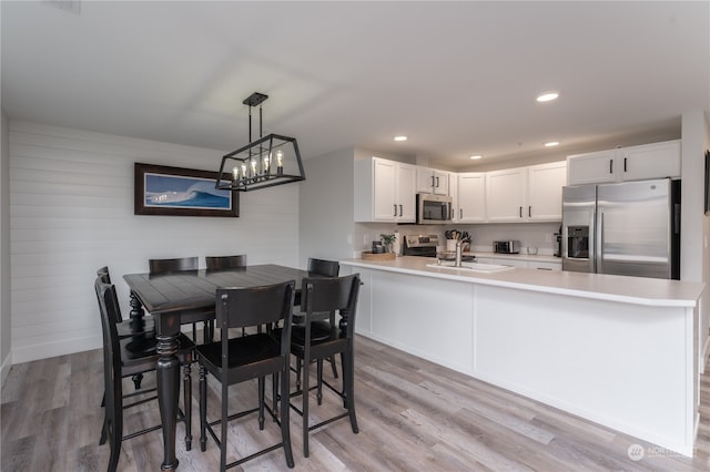 dining space featuring a notable chandelier, sink, and light hardwood / wood-style flooring