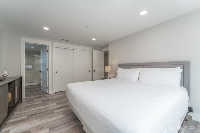 bedroom with a closet, ensuite bathroom, and light wood-type flooring