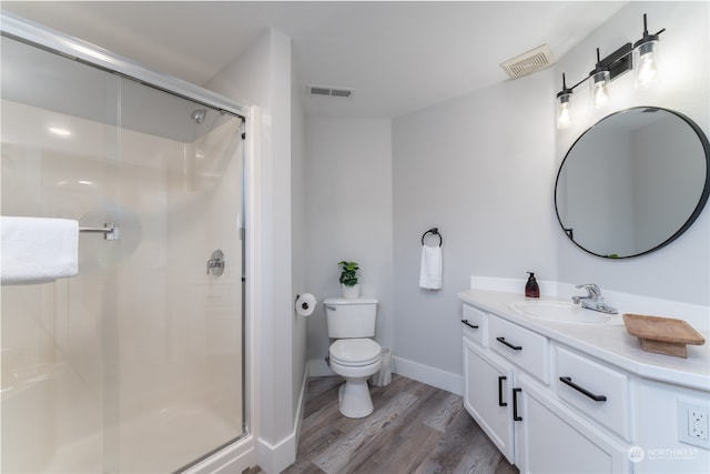 bathroom with toilet, a shower with door, vanity, and wood-type flooring