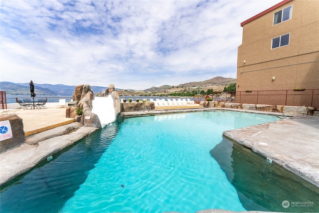 view of pool featuring a water slide, a mountain view, and a patio