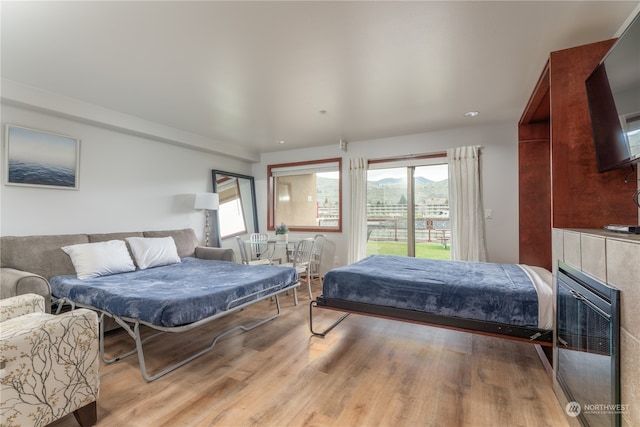 bedroom with light hardwood / wood-style floors and a tiled fireplace