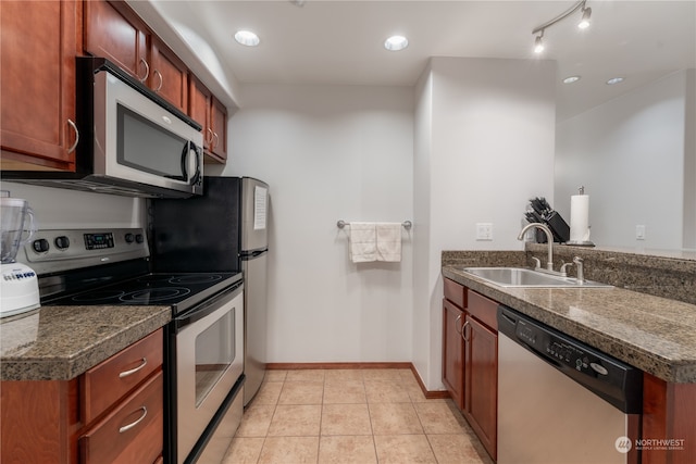 kitchen with stainless steel appliances, kitchen peninsula, track lighting, sink, and light tile flooring