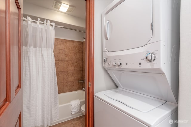 laundry area featuring stacked washer and clothes dryer and light tile floors