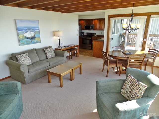 carpeted living room with a notable chandelier and beamed ceiling