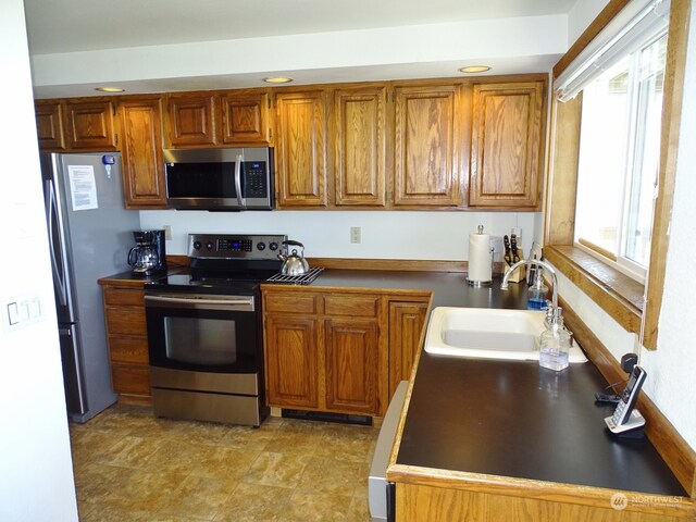 kitchen featuring stainless steel appliances, sink, light tile floors, and a wealth of natural light