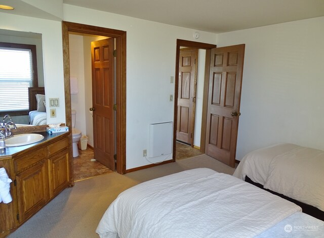 bedroom featuring ensuite bathroom, light colored carpet, and sink