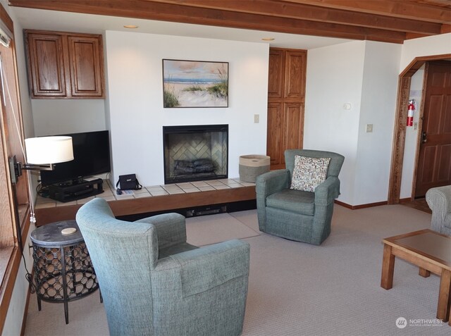 carpeted living room featuring beam ceiling and a tile fireplace