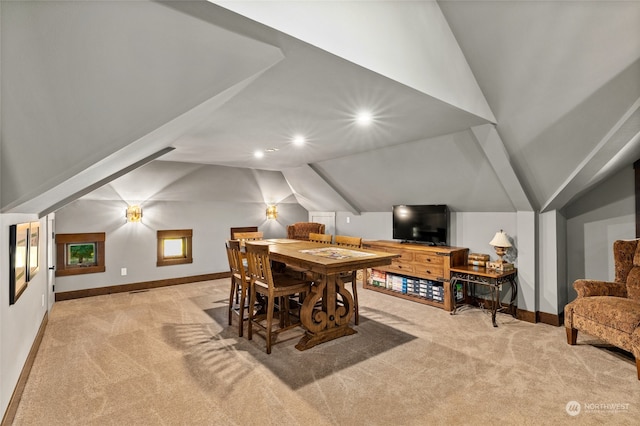 carpeted dining space with vaulted ceiling