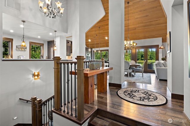 interior space with a notable chandelier, a towering ceiling, wood ceiling, dark hardwood / wood-style floors, and french doors