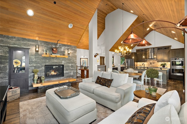 living room with an inviting chandelier, dark hardwood / wood-style floors, a large fireplace, high vaulted ceiling, and wood ceiling