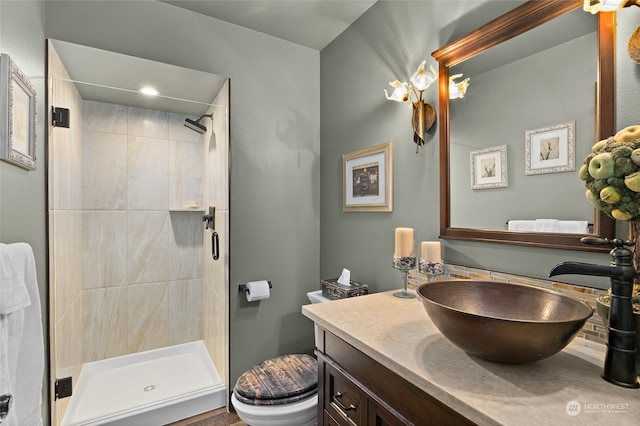 bathroom featuring toilet, a tile shower, and vanity