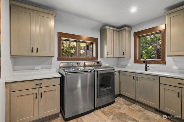 laundry room featuring light tile flooring, separate washer and dryer, cabinets, and sink