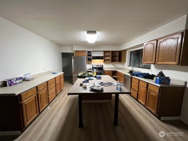 kitchen featuring ventilation hood, a kitchen island, appliances with stainless steel finishes, a breakfast bar, and light wood-type flooring