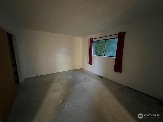 empty room featuring a textured ceiling and concrete floors