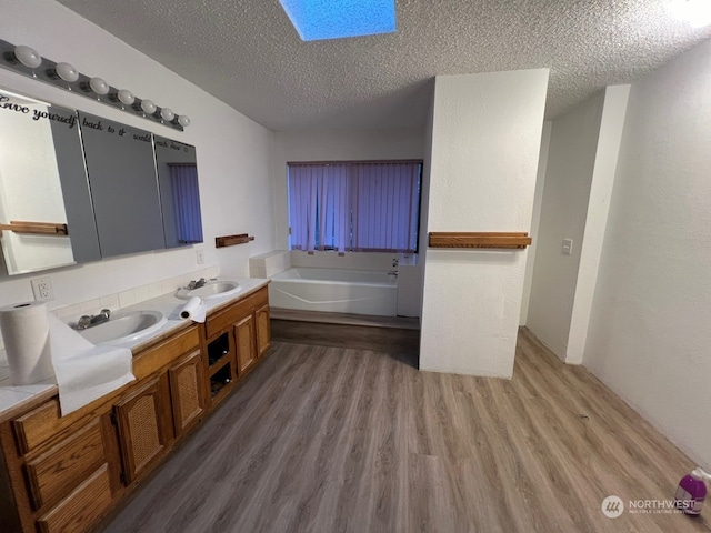 bathroom with hardwood / wood-style flooring, a textured ceiling, double vanity, and a bath