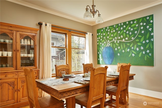 dining area with crown molding, an inviting chandelier, and light wood-type flooring