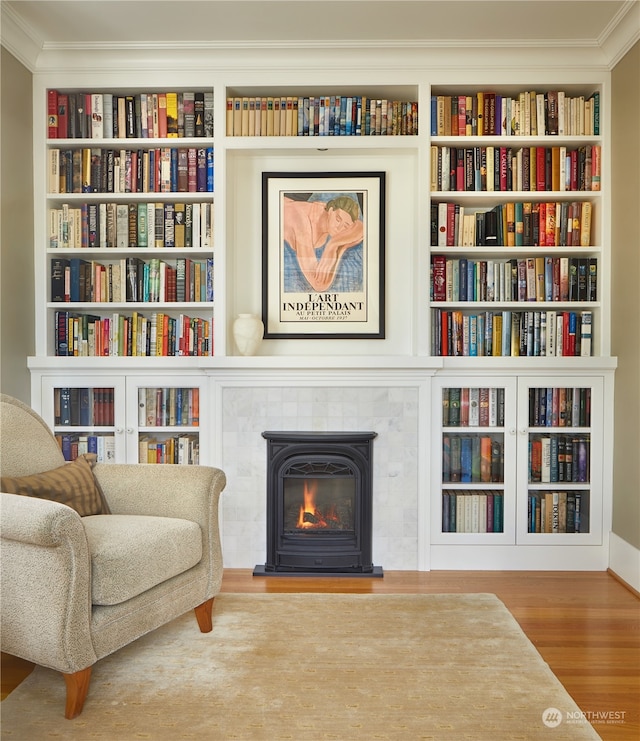 sitting room featuring built in features, crown molding, and hardwood / wood-style flooring