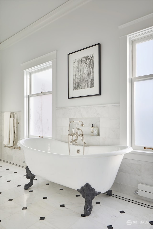 bathroom featuring tile walls, ornamental molding, tile floors, and a bathtub