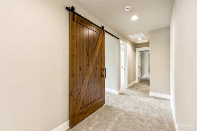 corridor with a barn door and light carpet