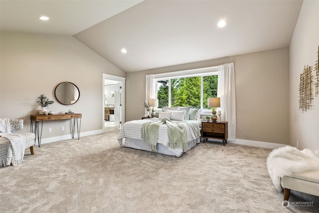 carpeted bedroom with ensuite bathroom and vaulted ceiling