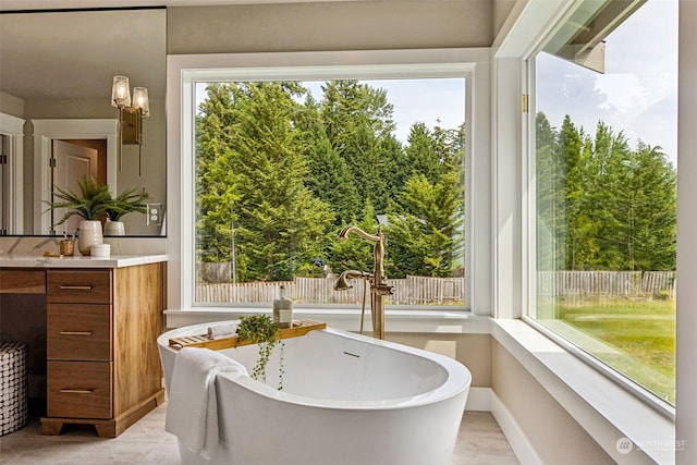 bathroom with tile patterned floors, a bathing tub, plenty of natural light, and vanity