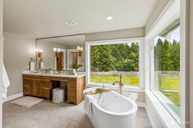 bathroom featuring tile patterned floors, a tub, plenty of natural light, and vanity