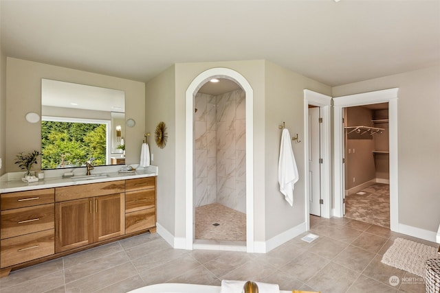 bathroom featuring tile patterned flooring, vanity, and tiled shower