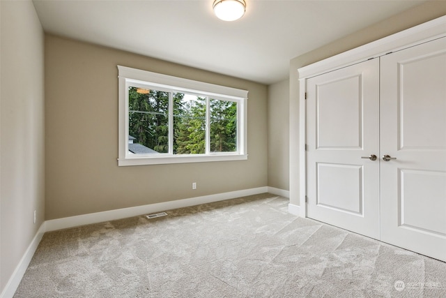 unfurnished bedroom with light carpet and a closet