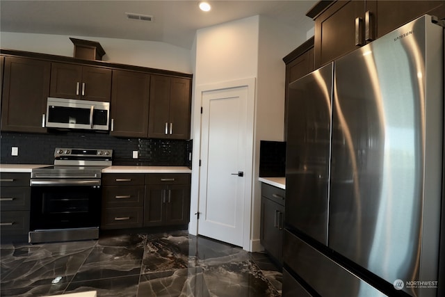 kitchen with appliances with stainless steel finishes, backsplash, vaulted ceiling, and dark brown cabinets