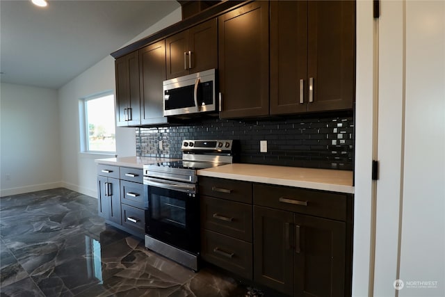 kitchen with vaulted ceiling, dark brown cabinets, stainless steel appliances, and decorative backsplash