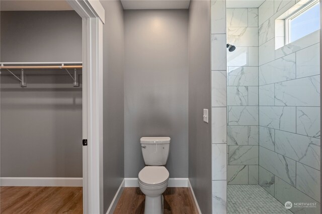 bathroom featuring tiled shower, hardwood / wood-style floors, and toilet