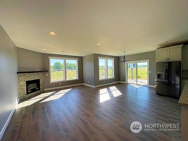 unfurnished living room with a fireplace, an inviting chandelier, and dark hardwood / wood-style flooring