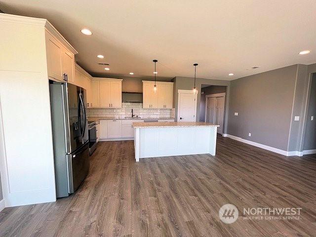 kitchen featuring stainless steel appliances, a center island, white cabinetry, decorative light fixtures, and tasteful backsplash