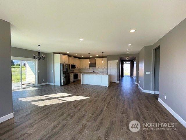 kitchen with decorative light fixtures, stainless steel appliances, a notable chandelier, a kitchen island, and white cabinets